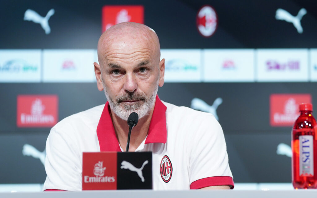 Stefano Pioli guarda in avanti in conferenza stampa indossando una polo bianca e rossa